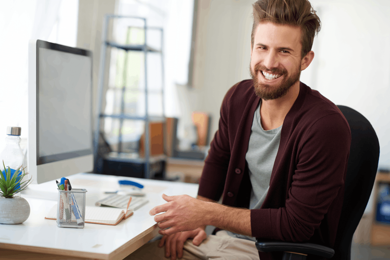 Junger Mann am Schreibtisch lacht