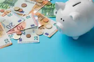 Geld und Sparschwein liegen auf einem blauen Boden